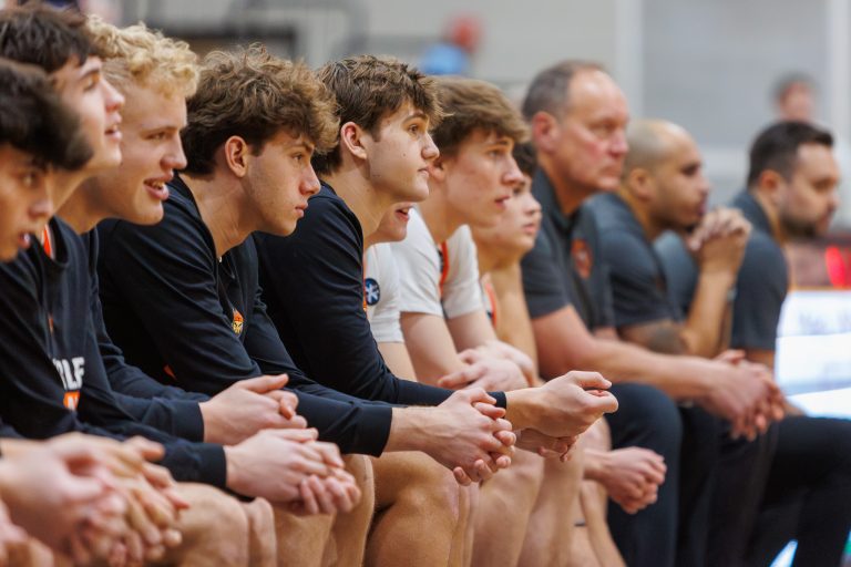 SCE Varsity Basketball Players watch courtside as teammates compete against Marmion Academy.