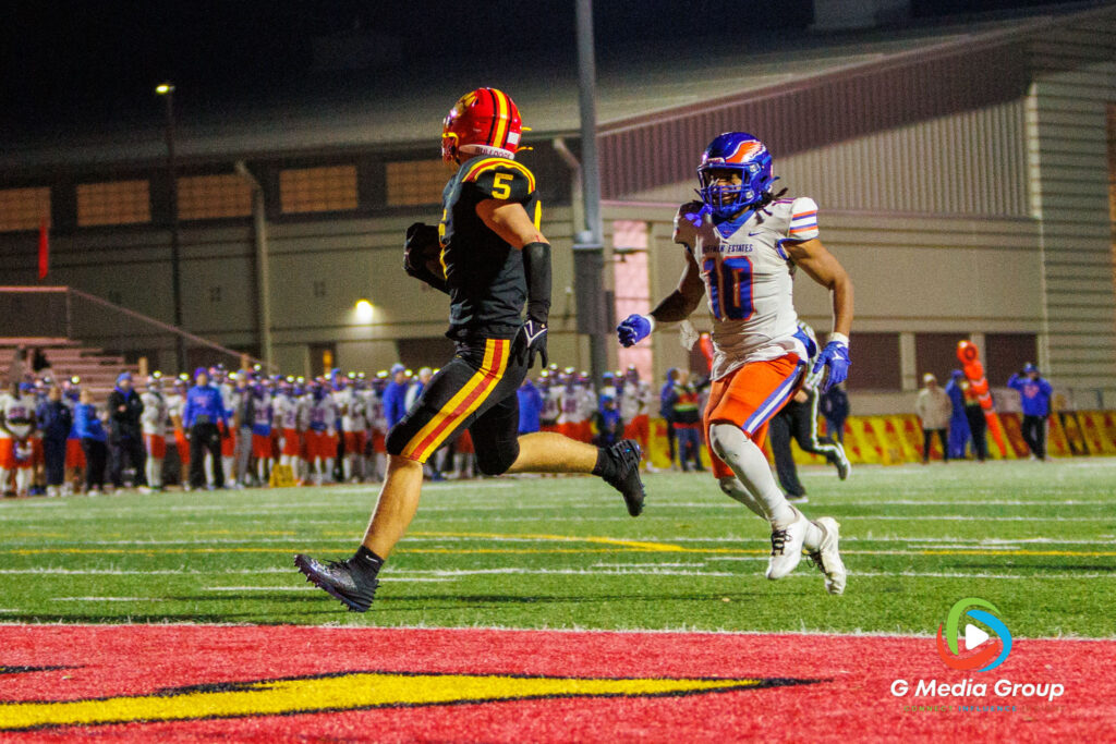 Batavia DB Jack Brown (5) crosses the goal line for a 50-yard scoop-and-score touchdown during the third quarter, pursued by Hoffman Estates players Austin Lezniak (12) and Quan Fields (10), in the Class 7A playoff victory.