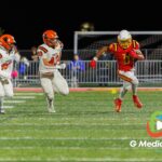 Batavia ball carrier (#0) rushes downfield as Wheaton Warrenville South defenders #43 and #25 pursue during the first quarter of a varsity football matchup at Bulldog Stadium in Batavia, Illinois, on October 16, 2026.