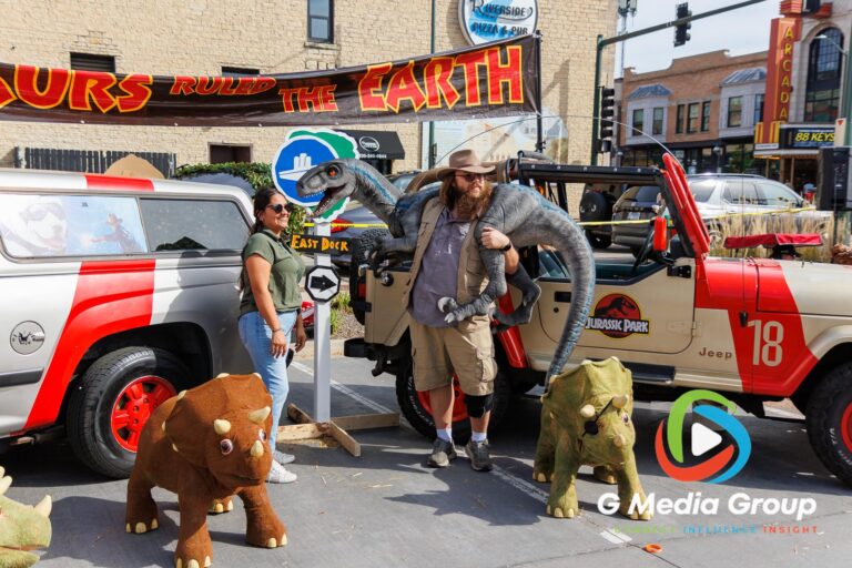 A festival attendee poses for a photo alongside a replica Jurassic Park Jeep display during the 41st annual Scarecrow Weekend on Saturday, Oct. 10, 2026, in downtown St. Charles, Ill.